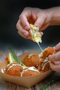 A person is dipping a piece of food into a container