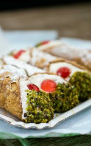 Close-up of classic Italian cannolis filled with creamy ricotta and topped with pistachios.